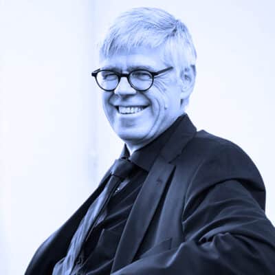 Porträtfoto von Heinz Erretkamps, Geschäftsführer der AGILean GmbH, lächelnd vor dunklem Hintergrund